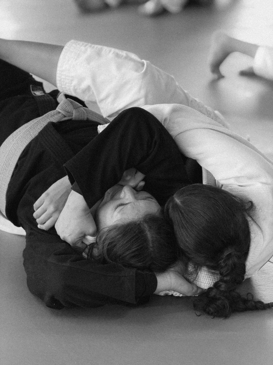 Deux filles pratiquent un mouvement contrôlé au sol pendant le cours de jiu-jitsu